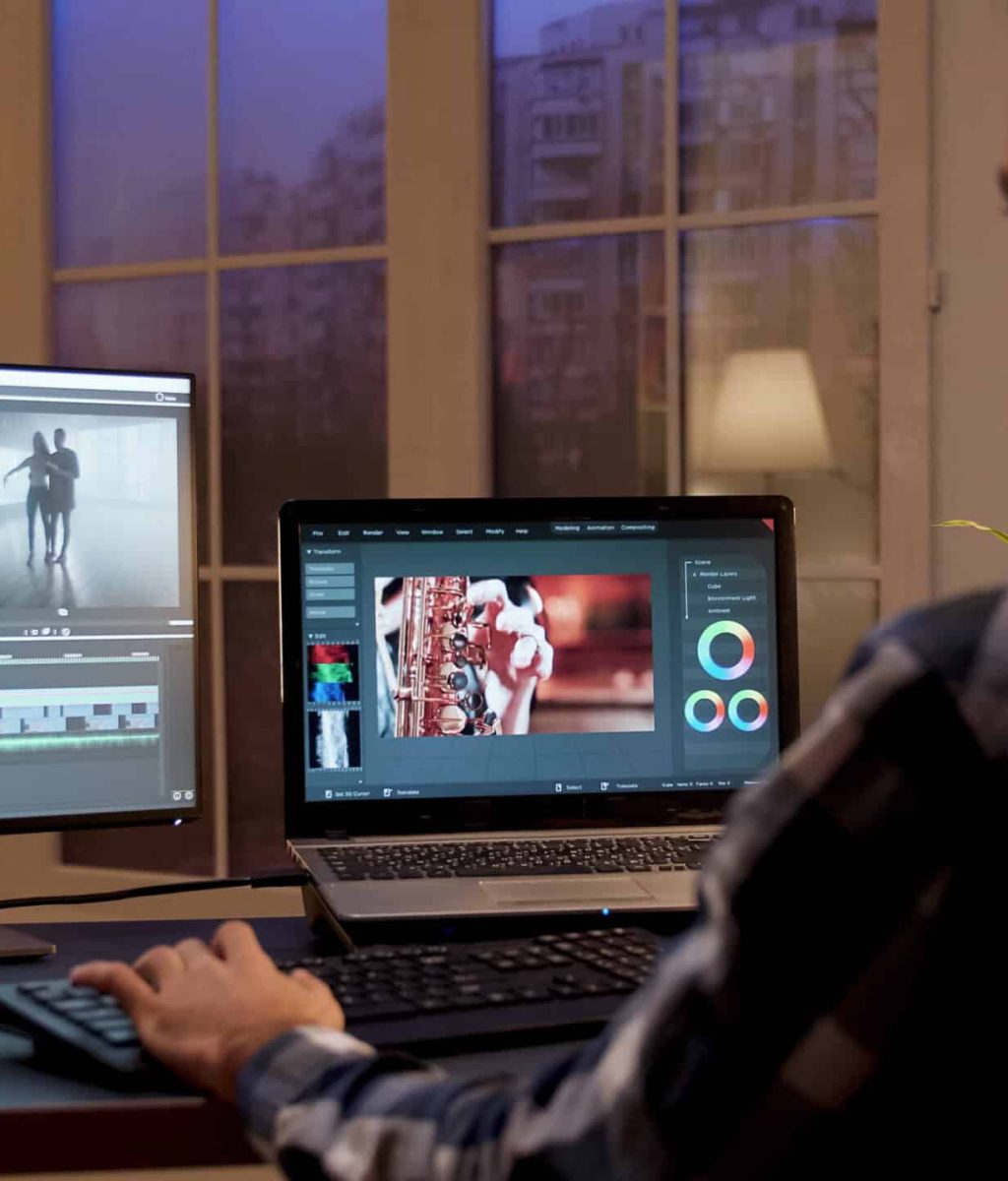 Back view of content creator working in home office during night time. Video editor in home office.